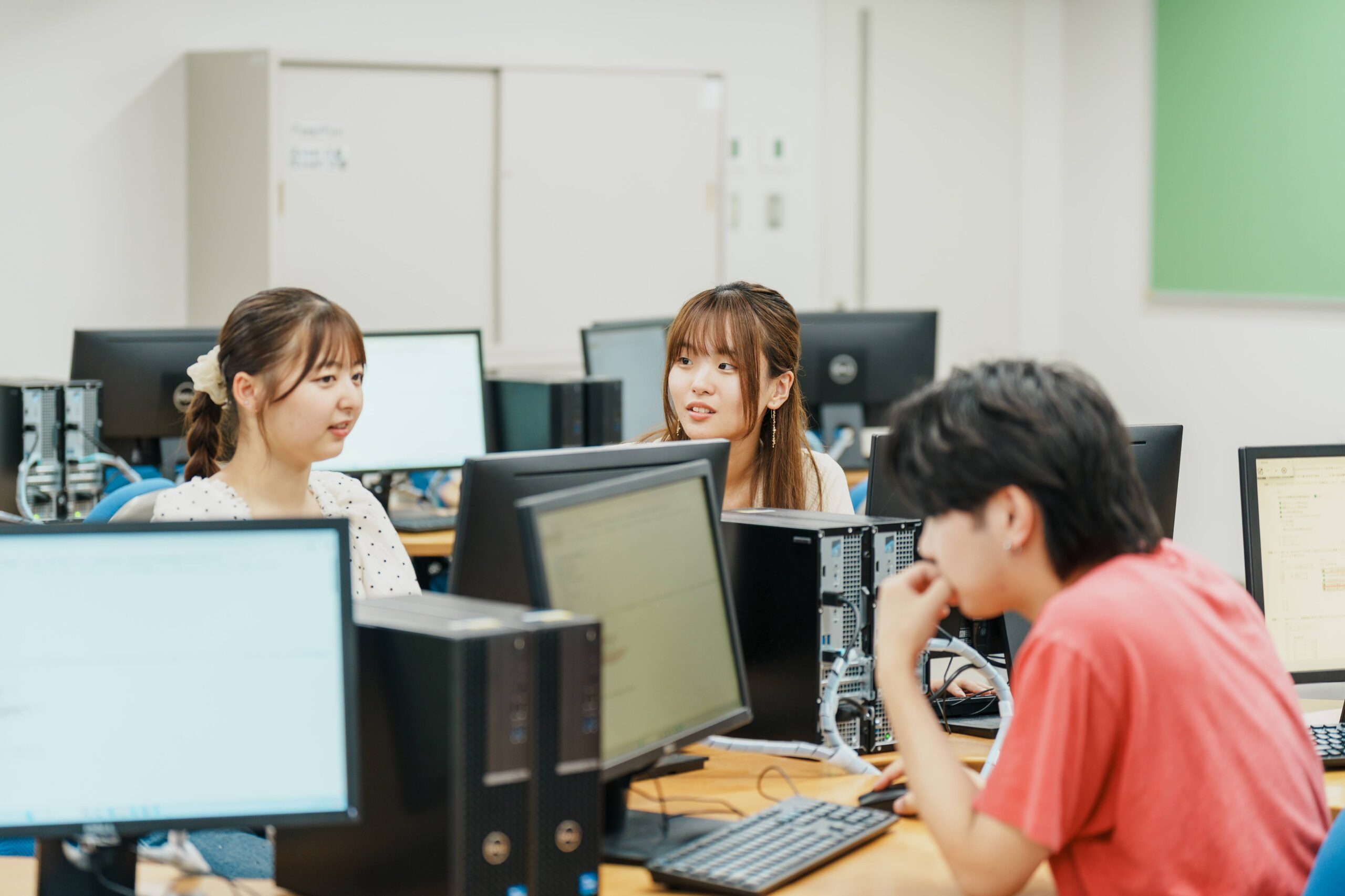 パソコン画面を囲み仲間と相談しながら学習を進める授業風景