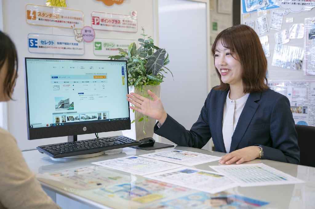 PC画面を活用して顧客に物件情報を案内する不動産スタッフ