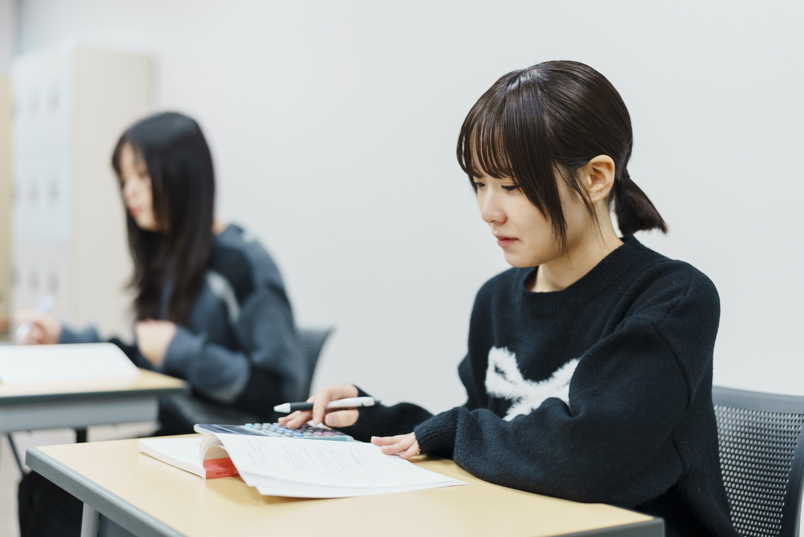 電卓とペンを用いて計算問題や法規の演習に集中する様子