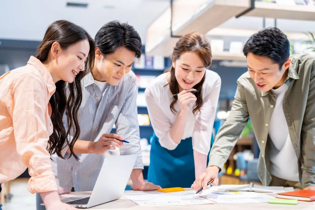 パソコンを囲んで話し合う若手社員たち